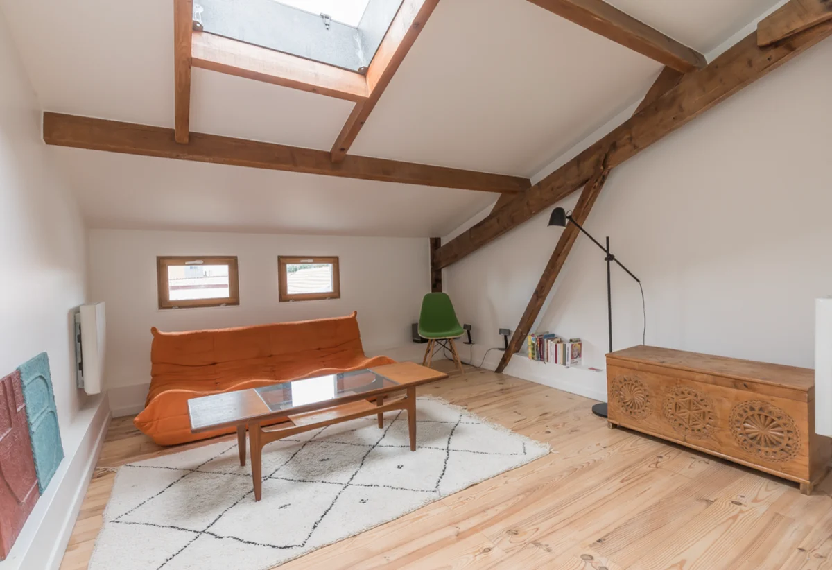 Studio sous combles avec poutres en bois et mezzanine